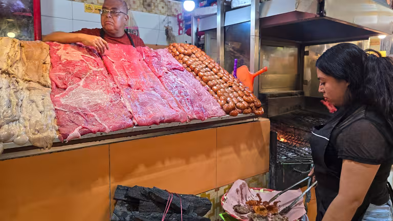 Köttstånd och grill i rökgången i marknaden i Oaxaca.